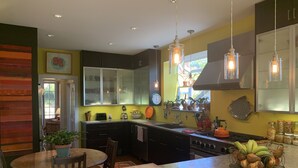 Una cocina moderna con una isla central, armarios oscuros e iluminación colgante.
