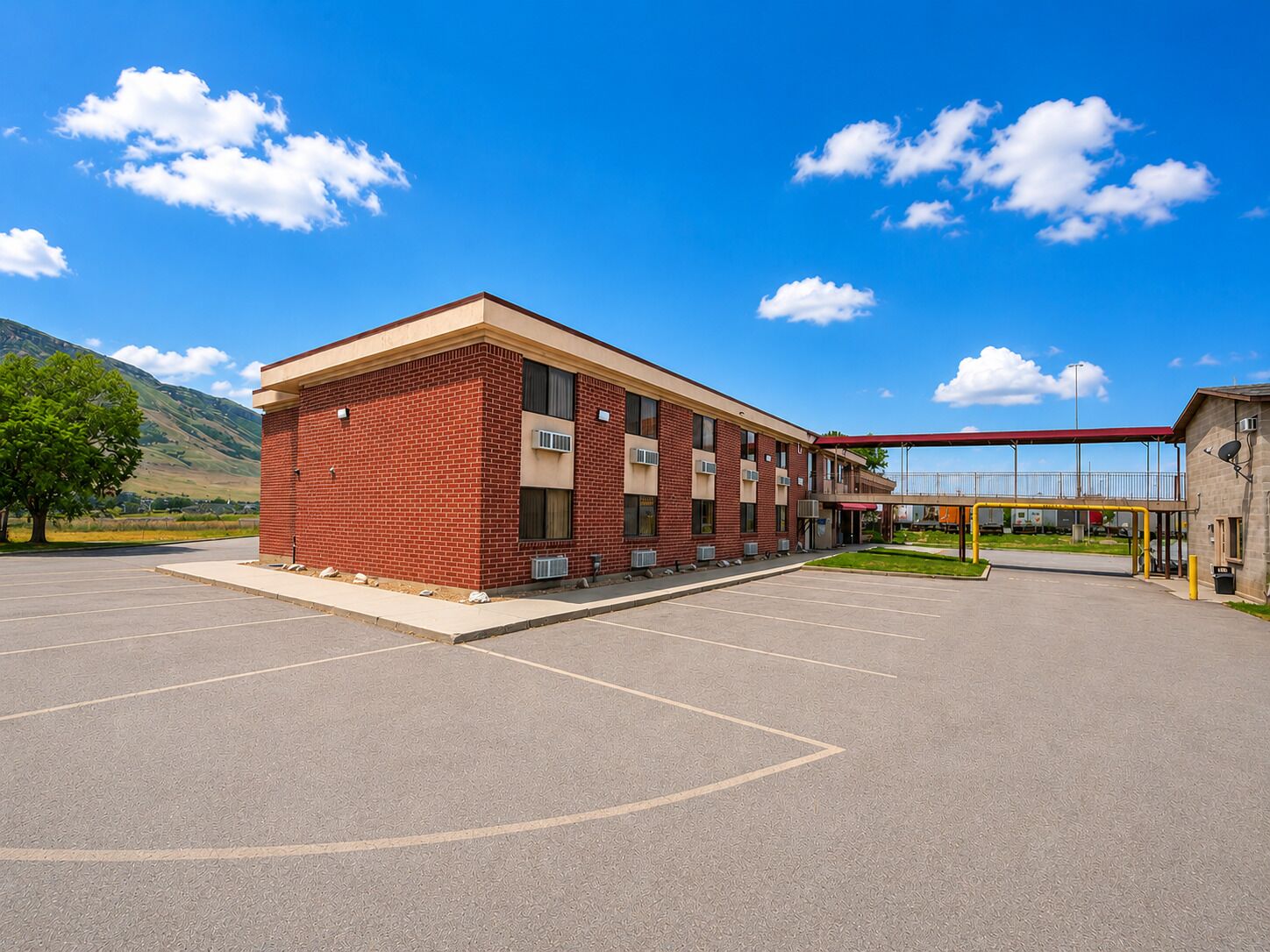 A building with a brick facade, a covered walkway, and a parking lot.