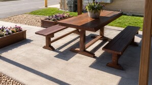 An outdoor patio with a wooden table and benches, surrounded by planters with flowers. - Days Inn by Wyndham Lake Point (Tooele)