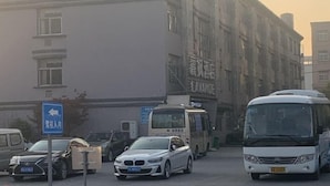 A parking lot with several cars and a bus, a building with a sign that reads "LAVANDE," and a blue sign indicating a direction. - Lavande Hotels (Hangzhou Xiaoshan International Airport) (Hangzhou)