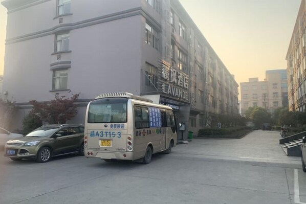 A building with a sign that reads "LAVANDE" and a bus parked in front. - Lavande Hotels (Hangzhou Xiaoshan International Airport) (Hangzhou)