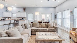 A spacious living room with a large L-shaped sectional sofa, a wooden coffee table, and a ceiling fan.