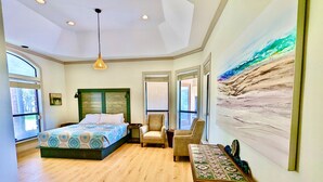 A bedroom with a bed, a chair, a table, and a painting on the wall. - Waterfront Luxury Home on 5 Acres. 
Sleeps 22. Beds: 5 king, 4 queen, 4 twin XL (New Braunfels)