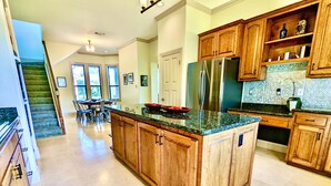A spacious kitchen with wooden cabinets, a central island, and a stainless steel refrigerator. - Waterfront Luxury Home on 5 Acres. 
Sleeps 22. Beds: 5 king, 4 queen, 4 twin XL (New Braunfels)