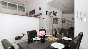 A dining area with a black table set for four, a vase of pink flowers, and a whale decoration on the wall.