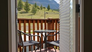 Ein Balkon mit Tisch und Stühlen, der einen Blick auf eine Berglandschaft bietet.