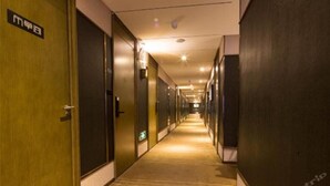 Pasillo de hotel con puertas a ambos lados, piso alfombrado y un cartel en la puerta izquierda.