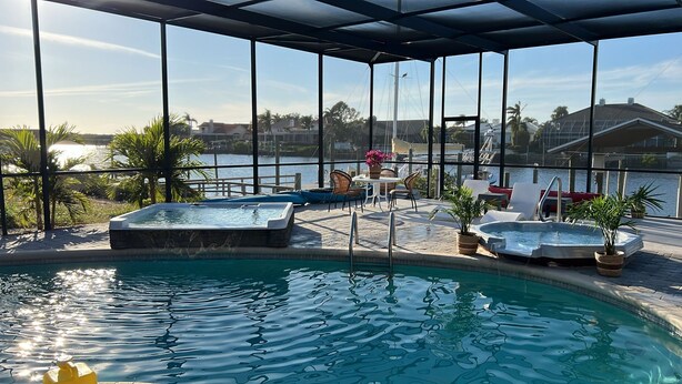 Zona de piscina con hidromasaje, sillas de descanso y vistas al puerto deportivo.