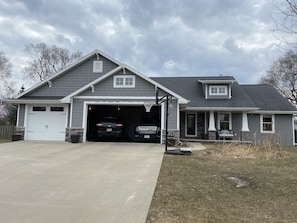 Une maison à deux étages avec un garage, un panier de basketball et des fondations en pierre.