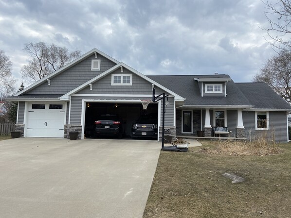 Ein zweistöckiges Haus mit Garage, Basketballkorb und Natursteinfassade.