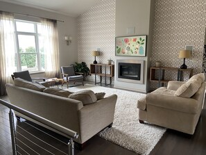 Un salon moderne avec une cheminée, deux canapés, un fauteuil et un mur orné d’un motif.