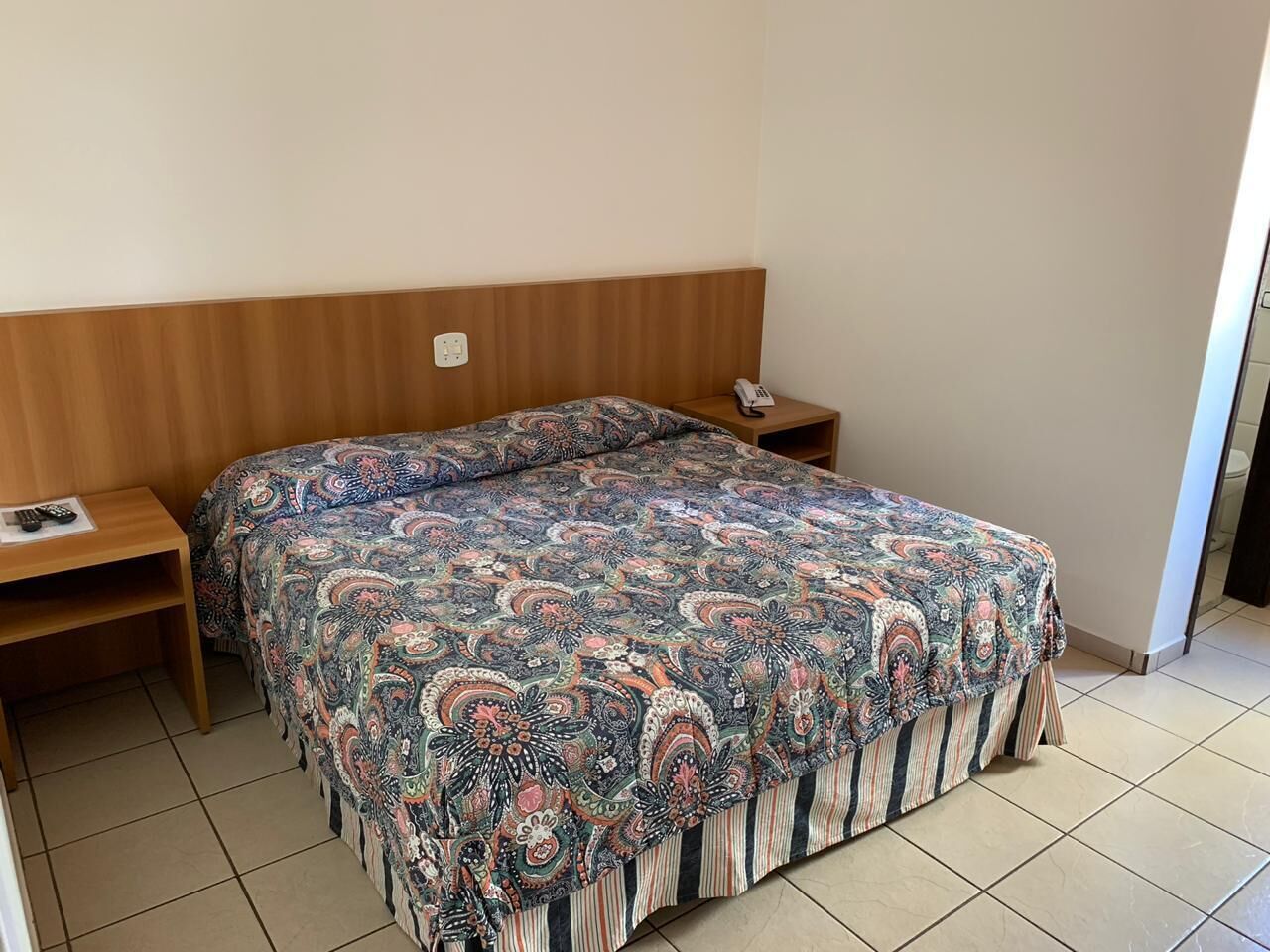 Un dormitorio con cama, cabecero de madera, mesitas de noche y teléfono.