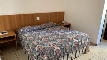 Un dormitorio con cama, cabecero de madera, mesitas de noche y teléfono.