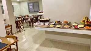 A buffet setup with various food items and a seating area with tables and chairs. - Hotel Flat Alameda (Aracatuba)