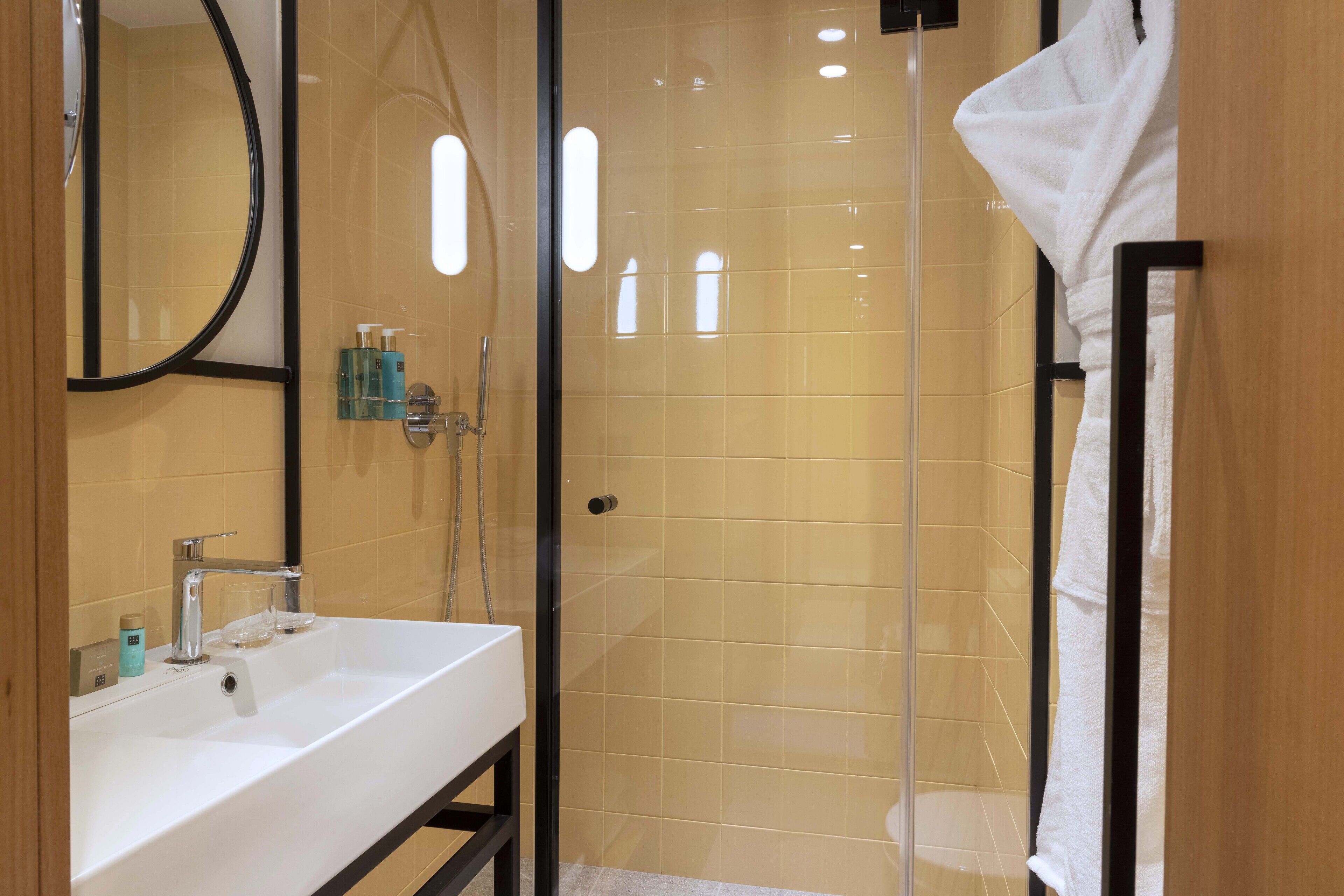 Une salle de bain moderne avec un lavabo blanc, une douche en verre et un porte-serviettes.