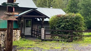 A rustic building with a metal roof, a wooden porch, and a 'Welcome' sign.