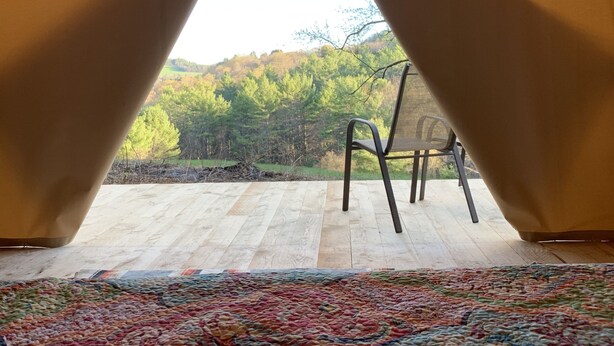 A tented room with a view of a forested landscape.