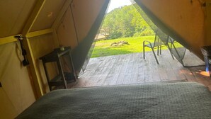 A tent with a view of a grassy area and a wooden deck.
