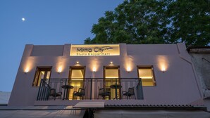 Un edificio con un cartello che indica “Mirma City Studio & Apartment”. Dispone di un balcone con sedie e tavoli, e presenta diverse finestre illuminate.
