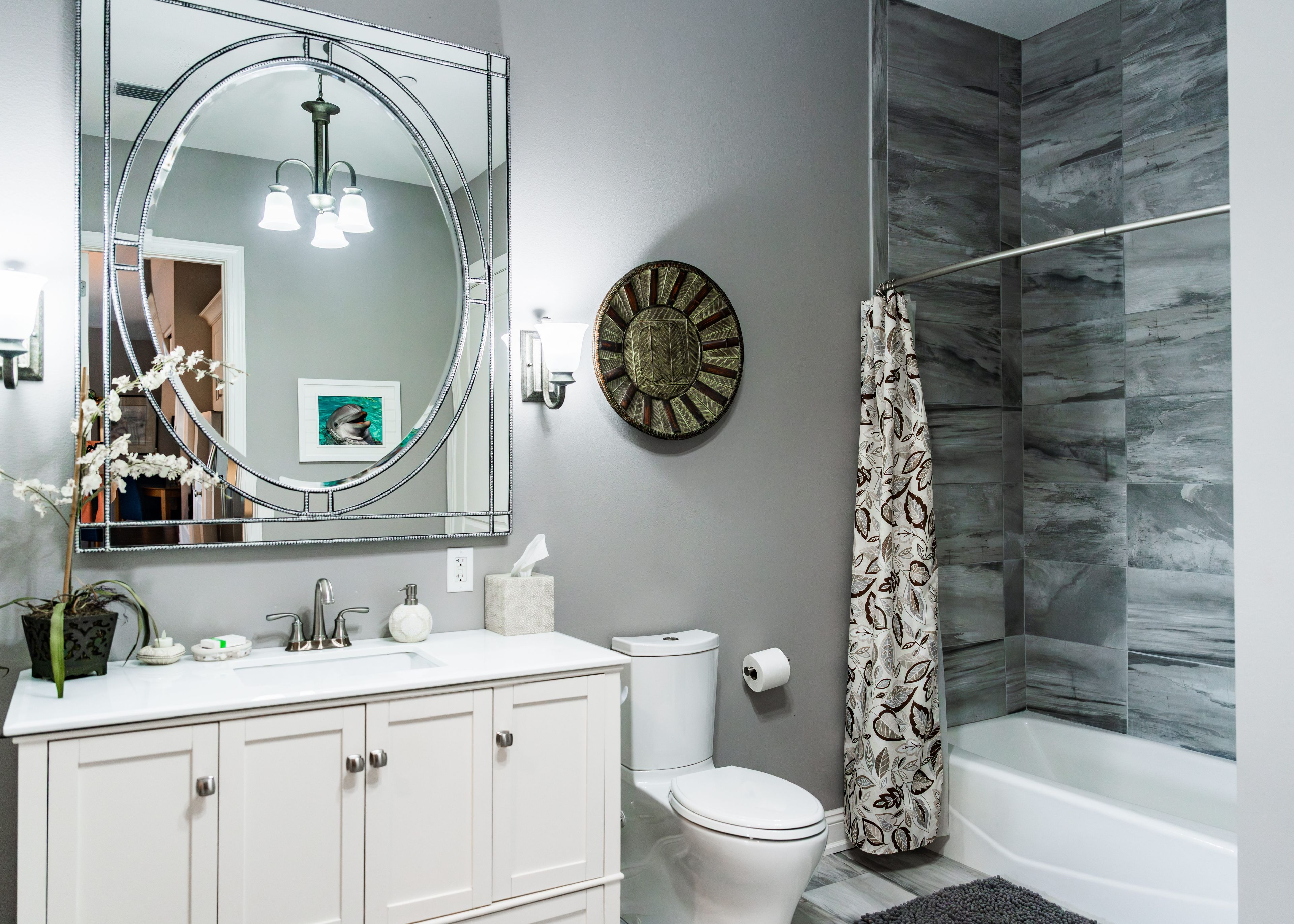 A bathroom with a white vanity, a large mirror, a toilet, and a shower area.