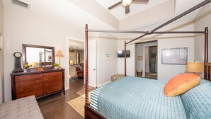A four-poster bed with a blue quilt and an orange pillow, a wooden dresser with drawers, a mirror, a clock, and a ceiling fan. - Downtown Dunedin Walking District (Dunedin)