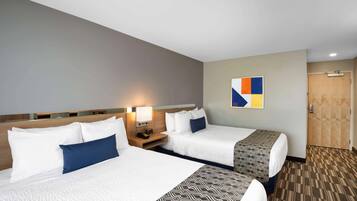 Une chambre d’hôtel avec deux lits, une tête de lit en bois, une œuvre d’art accrochée au mur et une moquette à motifs.