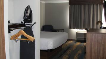Una camera d'albergo con un letto, una scrivania, una sedia, un appendiabiti e un piccolo tavolino.