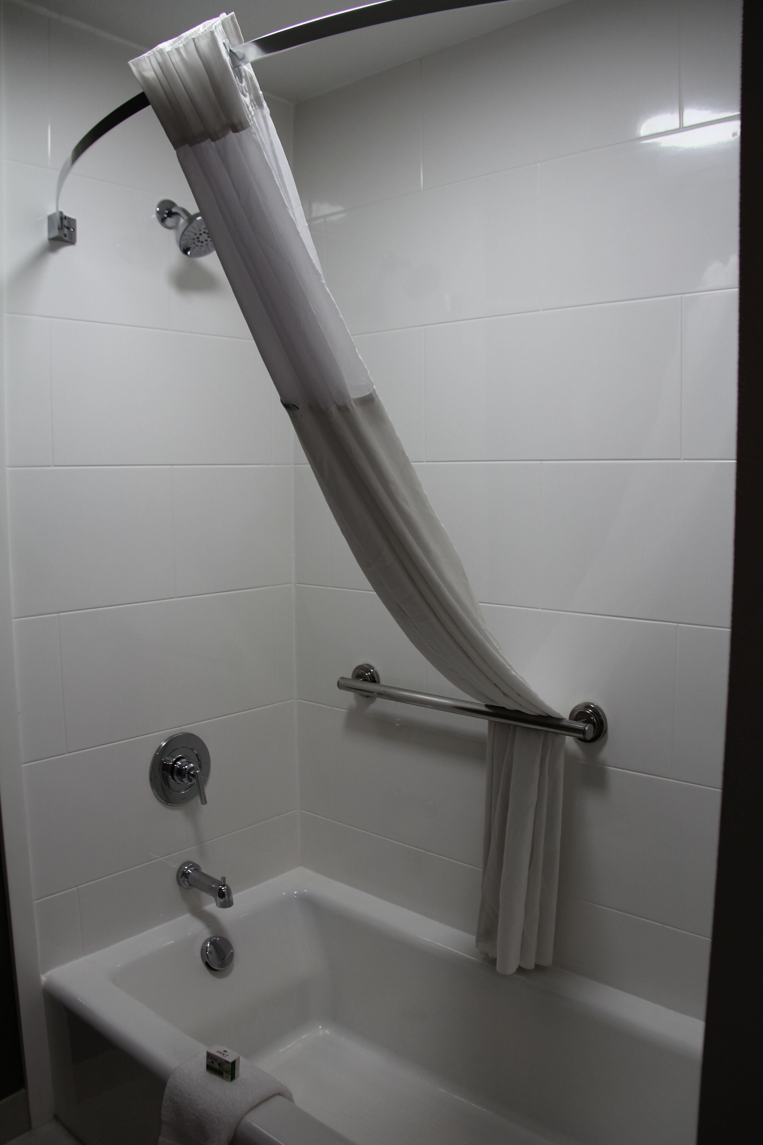 A bathroom with a white bathtub, a shower curtain, and a towel rack.