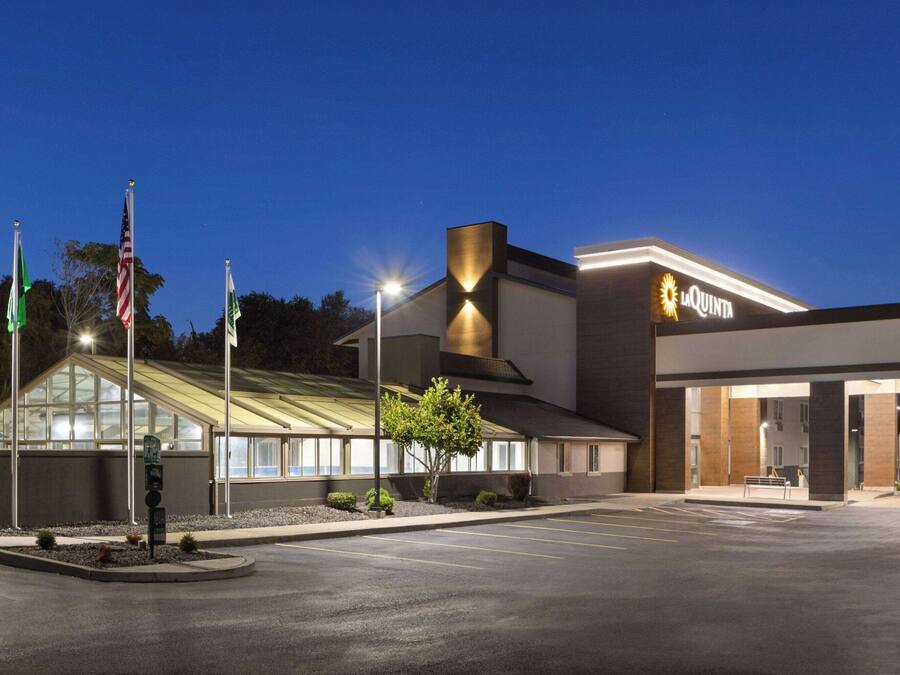A hotel with a modern design, featuring a prominent 'La Quinta' sign, a parking lot, and a well-lit entrance.