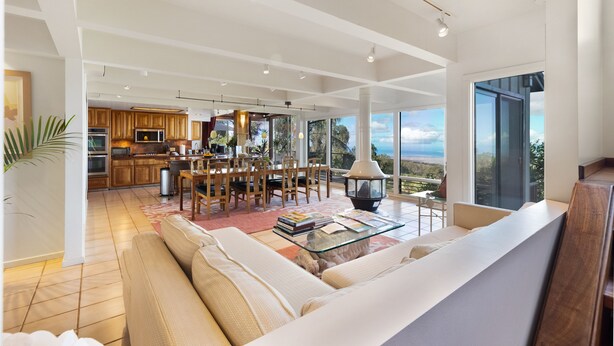 Un amplio espacio de sala con un sofá grande, una mesa de centro y vistas al área de cocina y comedor.