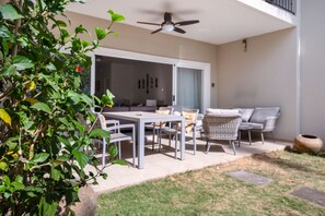 An outdoor patio with a dining table and chairs, a sofa, and a ceiling fan. - Beachfront Jewel in Langosta (tamarindo)