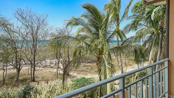 A balcony with a view of a beach and palm trees. - Beachfront Jewel in Langosta (tamarindo)