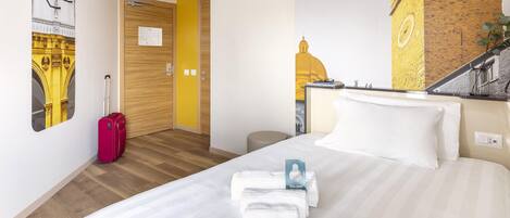 Una habitación de hotel con una cama, una maleta y una pared con un mural.