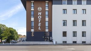 A modern hotel with a prominent 'HOTEL' sign, a flat facade, and a parking lot in front.