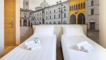 Habitación de hotel con dos camas, una puerta de madera y un mural que representa una escena de calle histórica.