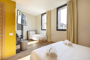 A hotel room with a bed, a desk, a chair, a small stool, and a window with curtains. - B&B Hotel Brescia (Brescia)