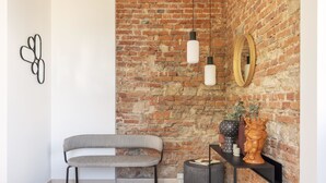 A modern room with a brick wall, a grey bench, a round table with decorative items, and pendant lights.