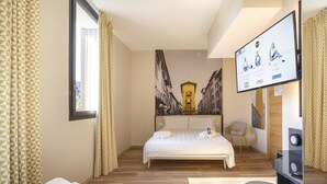 A hotel room with a bed, a desk, a chair, and a television.