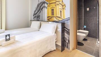 Una habitación de hotel con cama, baño con ducha y un mural de un edificio.