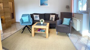 A living room with a sofa, two armchairs, a coffee table, and a bookshelf. - Dune house**** with use of swimming pool and sea view in top location ⭐️⭐️⭐️⭐️ (Göhren)