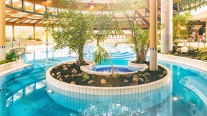 An indoor swimming pool with a central island, surrounded by plants and rocks. - Dune house**** with use of swimming pool and sea view in top location ⭐️⭐️⭐️⭐️ (Göhren)