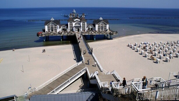 A pier with a white building at the end, a sandy beach, and a clear blue sky. - Dune house**** with use of swimming pool and sea view in top location ⭐️⭐️⭐️⭐️ (Göhren)