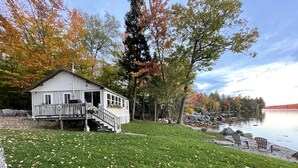 Une cabane avec une terrasse et vue sur un lac.