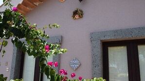 Une façade d’immeuble avec un mur rose, des carreaux décoratifs et une fenêtre dotée d’un cadre marron.