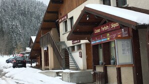 Un bâtiment doté d’une façade en bois, d’un escalier apparent et d’une enseigne indiquant « Forfaits / abonnements de ski ».