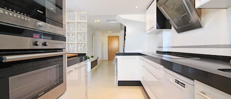 Una cocina moderna con electrodomésticos de acero inoxidable, armarios blancos y encimera negra.