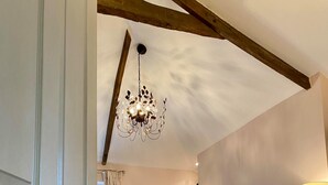 Ein Schlafzimmer mit einem Bett, einem Nachttisch, einer Lampe, einem Kronleuchter, einer Tür mit einem Schild und einem Fenster mit Vorhängen.