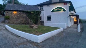 The Dartmoor Inn, mit einer Steinfassade, einem grünen Schild und einer kleinen Gartenanlage.