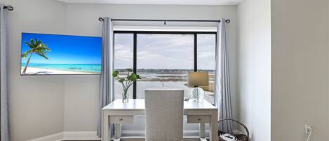 Una habitación con escritorio, silla y un amplio ventanal con vista a la playa.