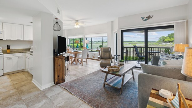 A spacious living area with a kitchen, dining area, and a balcony with a scenic view.